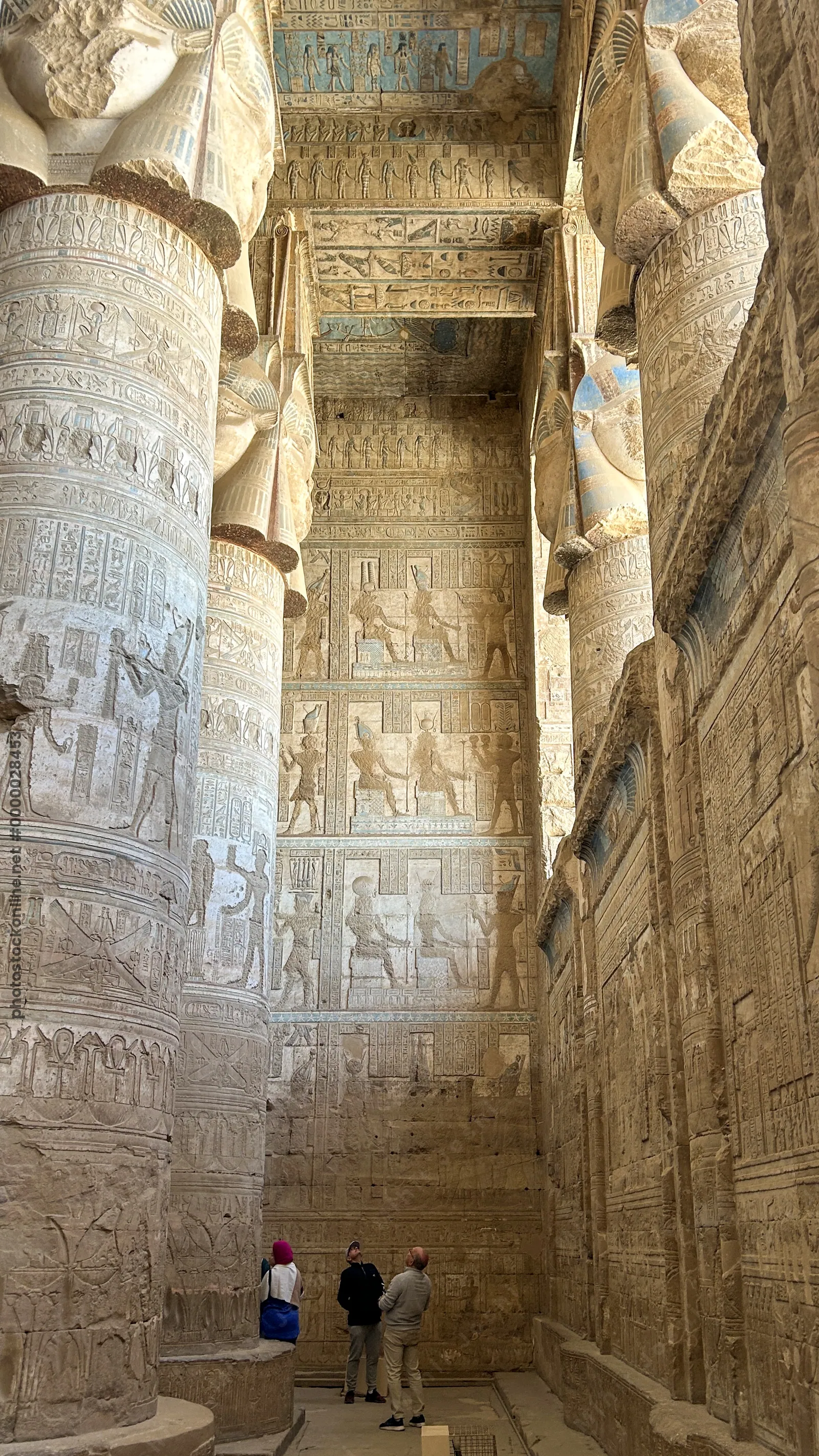Dendera, Egypt - Feb 10, 2025: Visitors admire massive carved columns, painted ceiling, and intricate reliefs inside the ancient Temple of Hathor at D