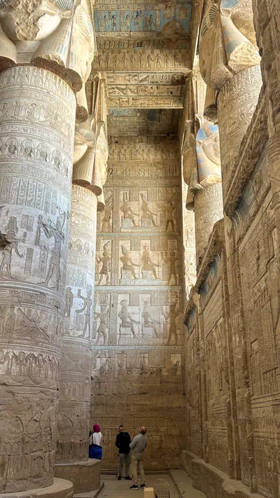 Dendera, Egypt - Feb 10, 2025: Visitors admire massive carved columns, painted ceiling, and intricate reliefs inside the ancient Temple of Hathor at D