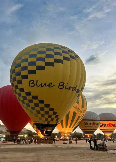 Luxor, Egypt - Feb 10, 2025: Colorful hot air balloons being inflated at dawn, preparing for a sunrise flight over the Nile Valley.