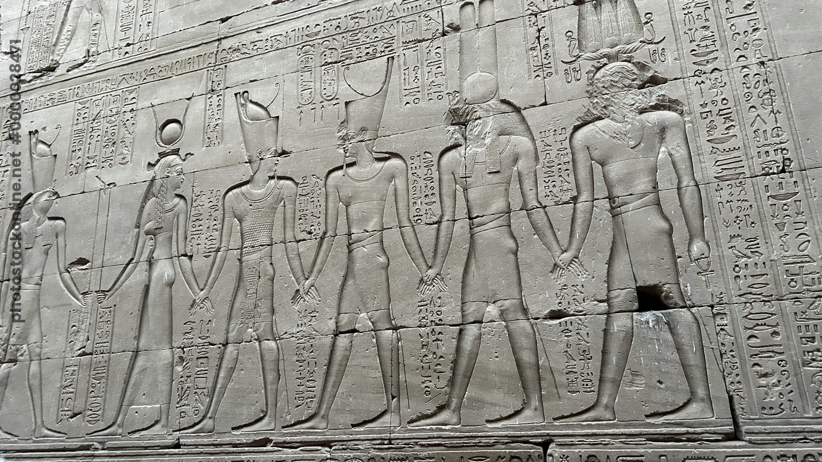 Edfu, Egypt - Feb 9, 2025: A carved sandstone relief at the Temple of Horus in Edfu depicting a procession of gods and the pharaoh, richly inscribed w