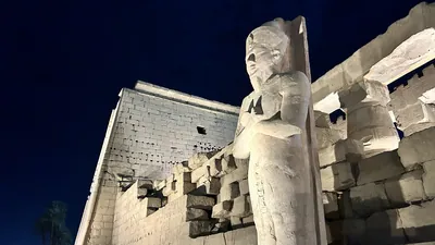 Luxor, Egypt - Feb 9, 2025: Night view of the illuminated colossal standing statue of Pharaoh Ramses II at the entrance of Luxor Temple in Egypt.