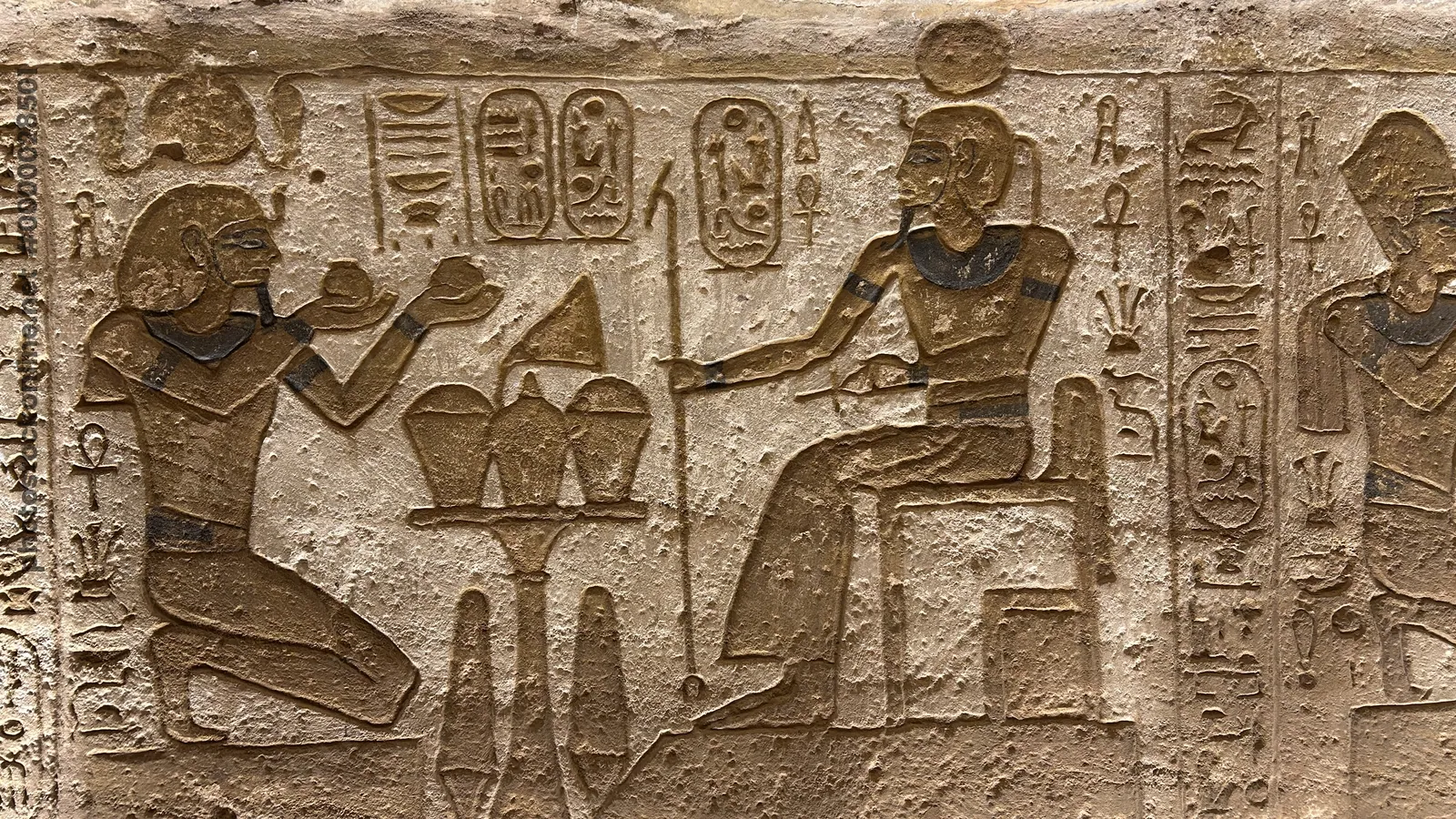 Aswan, Egypt - Feb 8, 2025: Ancient relief at Abu Simbel showing Pharaoh Ramesses II kneeling with offerings before the sun god Ra, depicted with sola