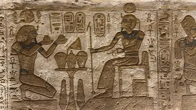 Aswan, Egypt - Feb 8, 2025: Ancient relief at Abu Simbel showing Pharaoh Ramesses II kneeling with offerings before the sun god Ra, depicted with sola