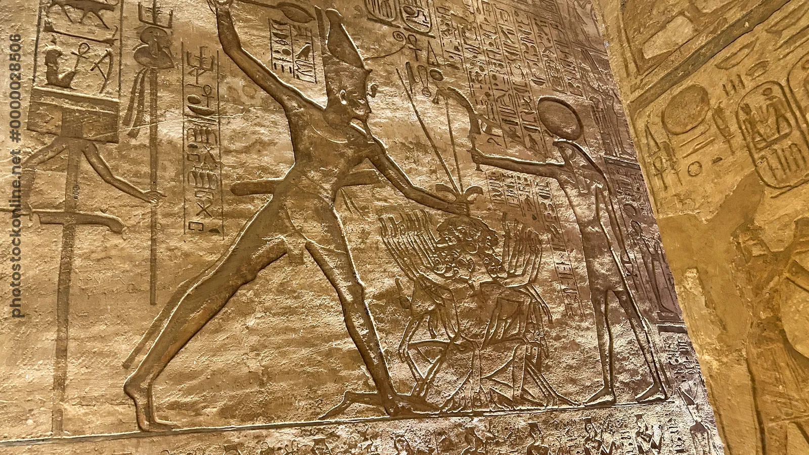 Aswan, Egypt - Feb 8, 2025: Ancient wall relief at Abu Simbel showing Pharaoh smiting enemies before the sun god Ra.