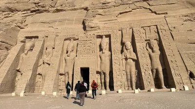Aswan, Egypt - Feb 8, 2025: The facade of the Temple of Nefertari at Abu Simbel with colossal statues carved into the sandstone cliff.