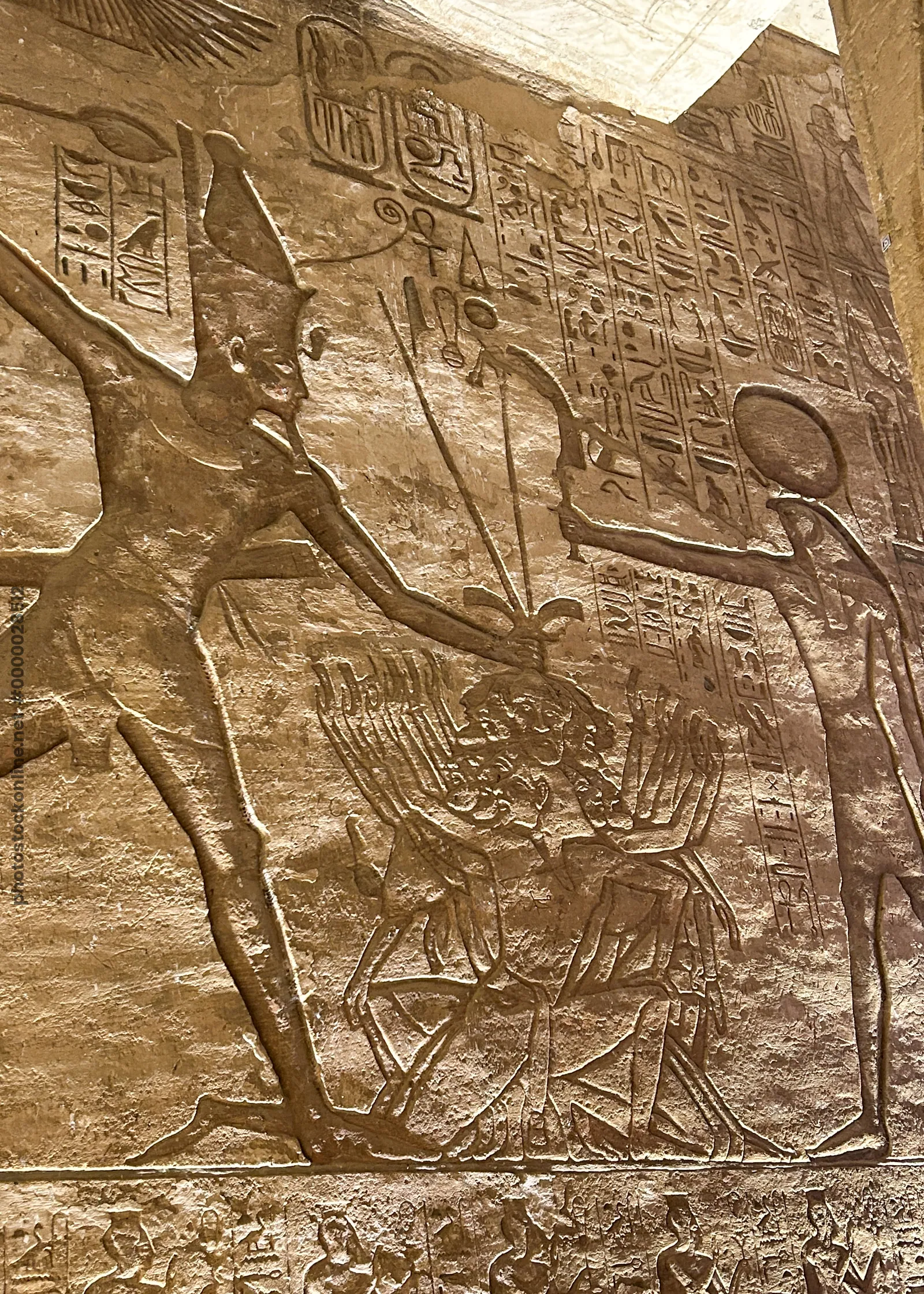 Aswan, Egypt - Feb 8, 2025: Ancient wall relief at Abu Simbel showing Pharaoh smiting enemies before the sun god Ra.