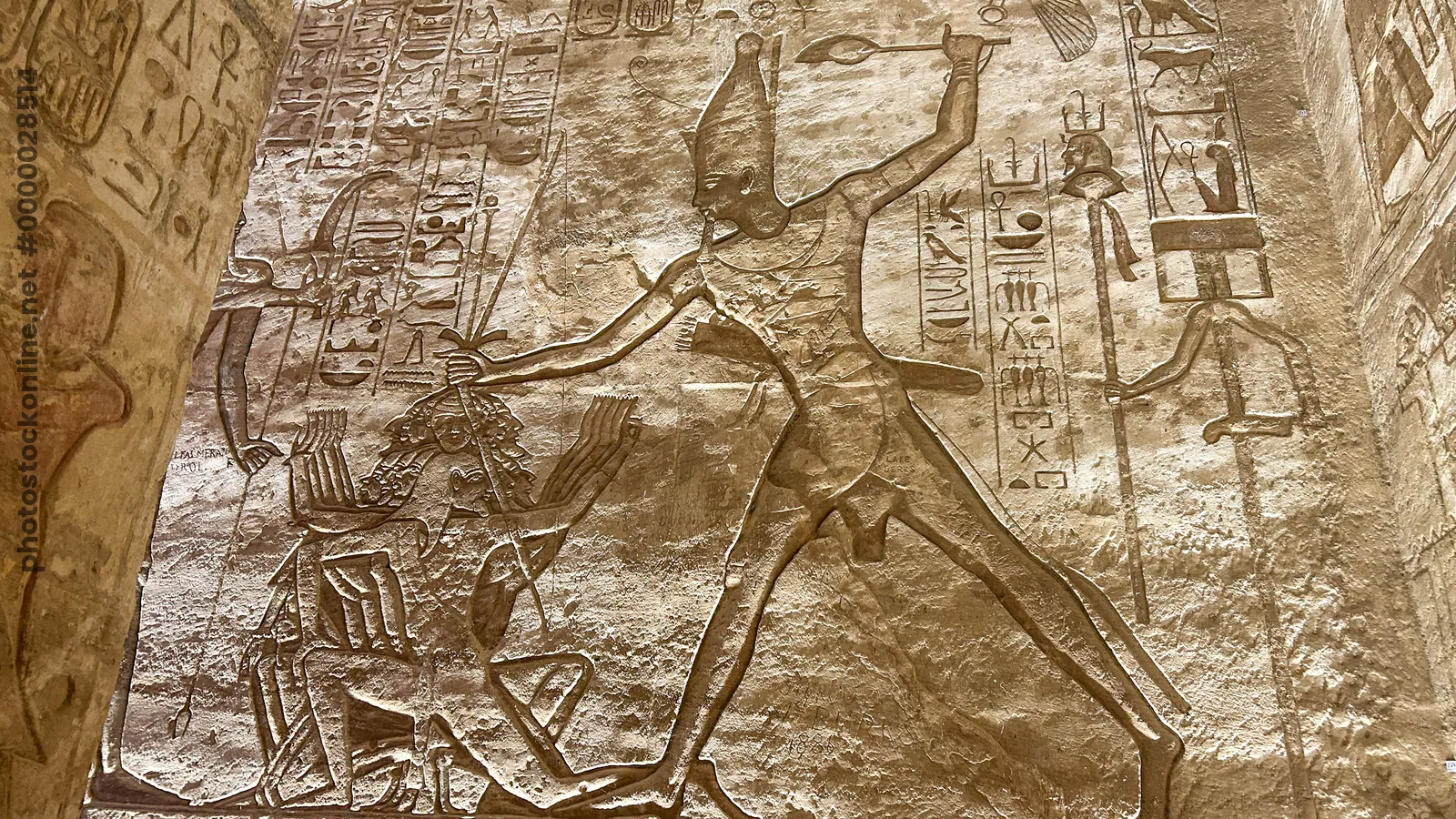 Aswan, Egypt - Feb 7, 2025: Ancient relief at Abu Simbel showing Pharaoh smiting enemies with hieroglyphs.