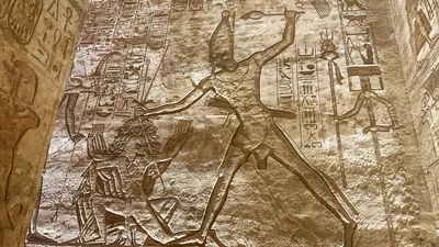 Aswan, Egypt - Feb 7, 2025: Ancient relief at Abu Simbel showing Pharaoh smiting enemies with hieroglyphs.