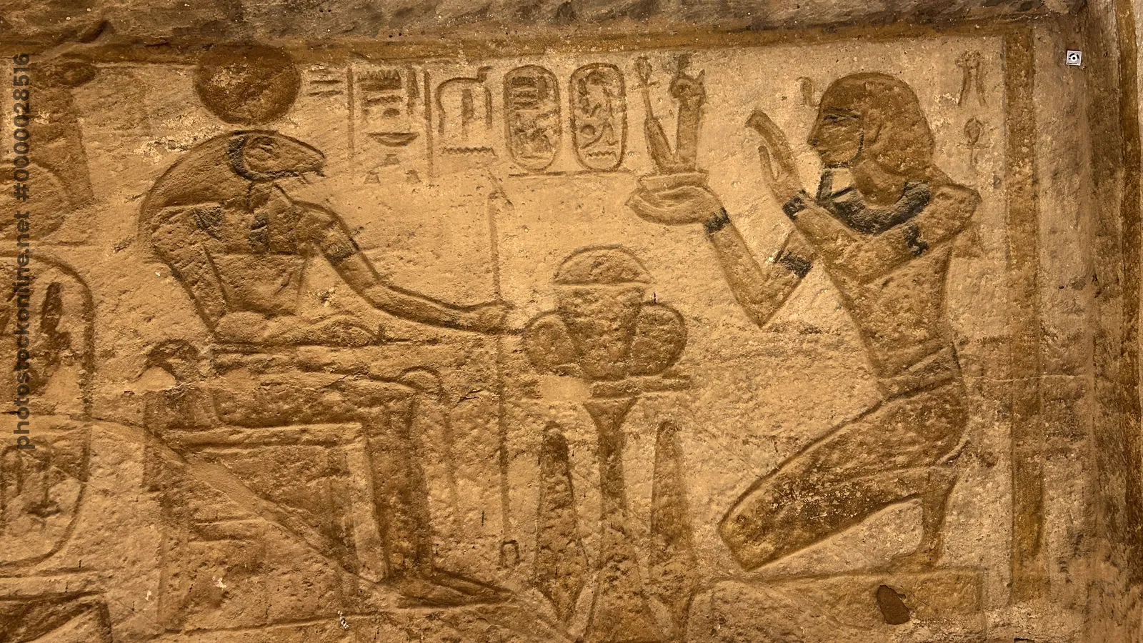 Aswan, Egypt - Feb 8, 2025: Ancient wall relief at Abu Simbel showing Pharaoh kneeling before the ram-headed god Khnum.