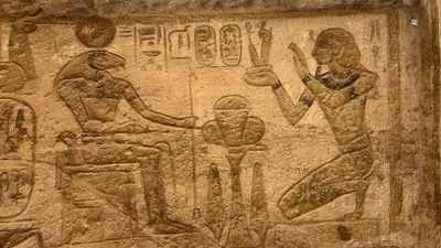 Aswan, Egypt - Feb 8, 2025: Ancient wall relief at Abu Simbel showing Pharaoh kneeling before the ram-headed god Khnum.