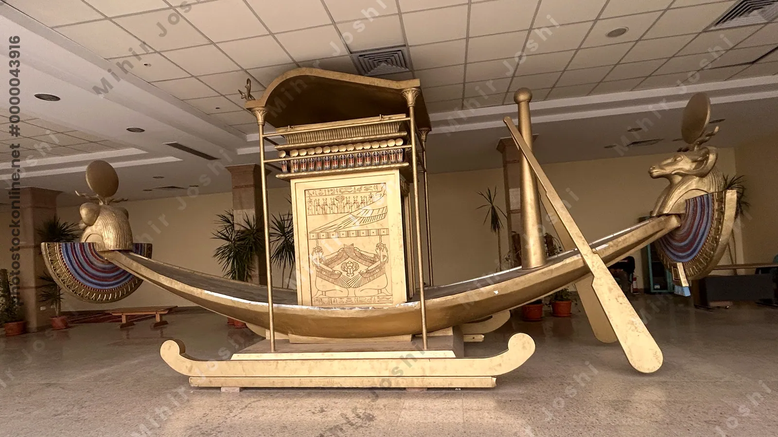 Karnak Temple, Luxor, Egypt - Feb 10, 2025: Ancient wooden model of a solar barque with ram-headed figures at each end and symbolic winged goddess carvings surrounding a scarab beetle motif.
