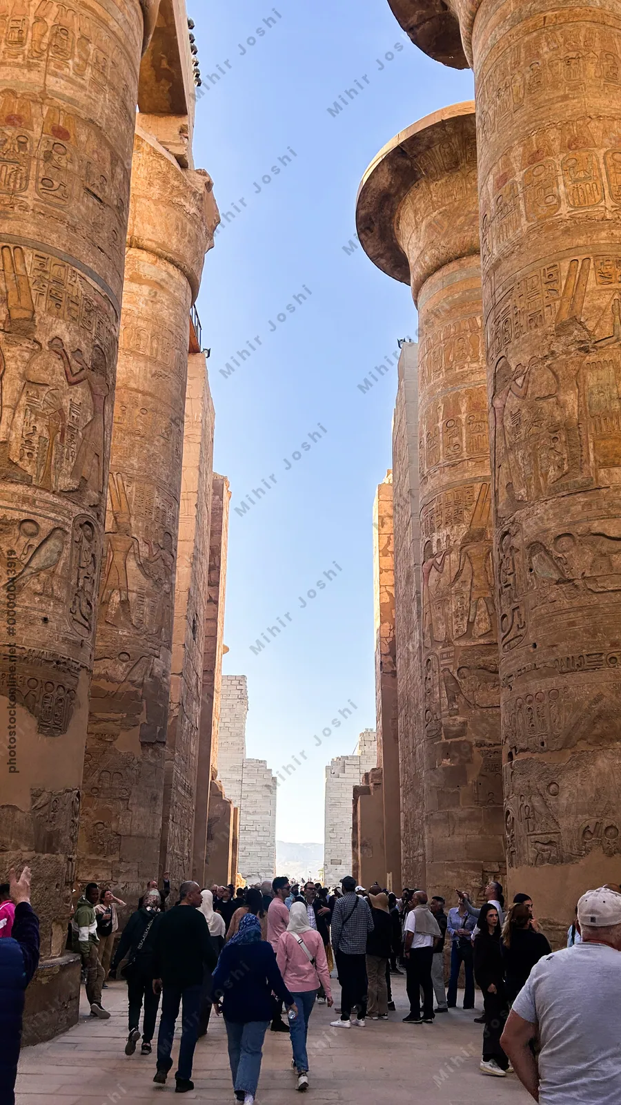 Karnak Temple, Luxor, Egypt - Feb 10, 2025: Visitors walk among massive sandstone columns with hieroglyphics inside the Great Hypostyle Hall.
