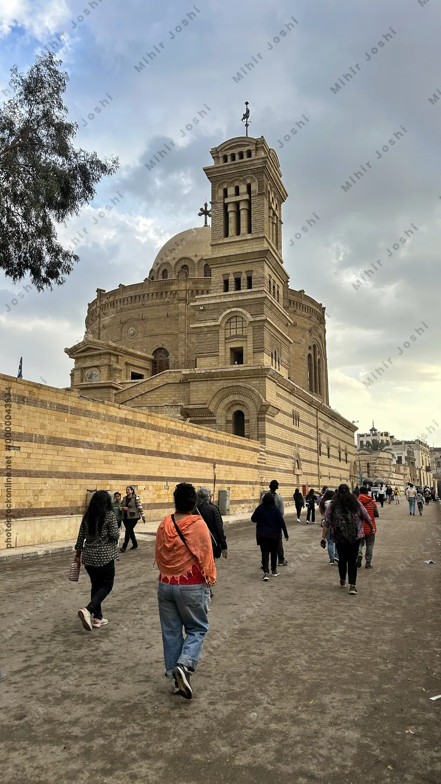 Cairo, Egypt - Feb 5, 2025: Tourists walk toward the Greek Orthodox Church of St. George inside the ancient Babylon Fortress in historic Coptic Cairo, Egypt.