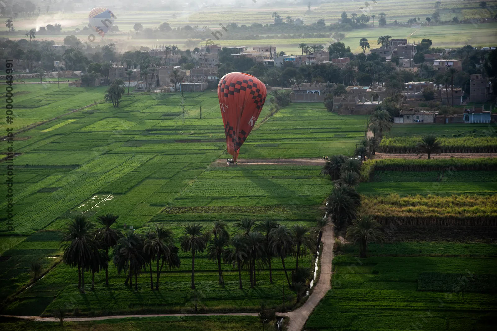 Luxor, Egypt - Feb 10, 2024: Hot air balloon lands in a lush green field near Luxor, Egypt, during early morning balloon ride