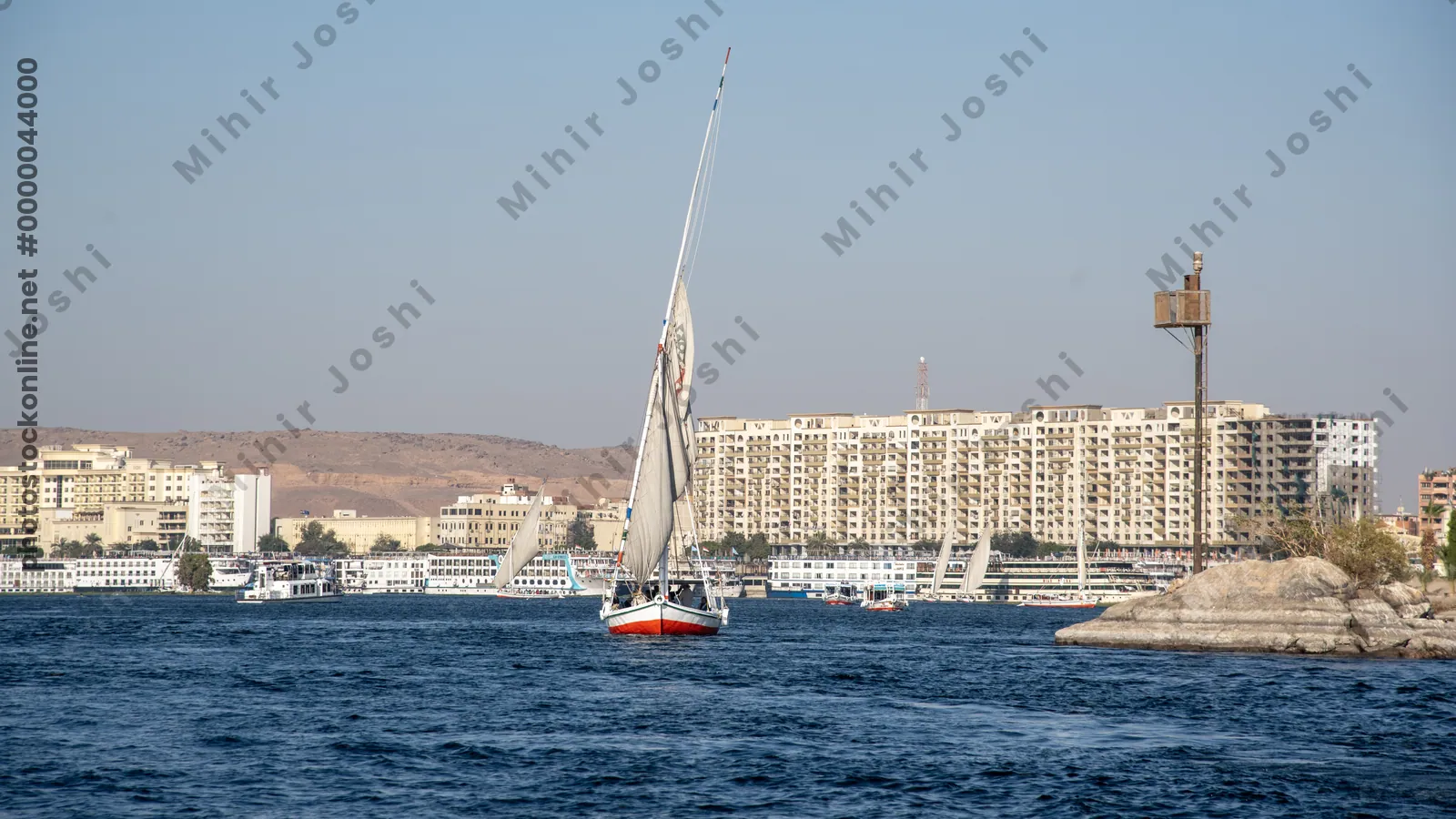 Aswan, Egypt - Feb 7, 2025:  A traditional felucca sails the clear, blue waters of the Nile River near Aswan, Egypt