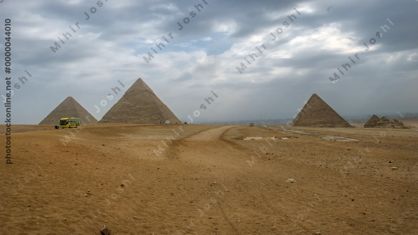Giza, Egypt - Feb 6, 2024: A tourist bus passes near the Great Pyramids of Giza, viewed from the desert near Cairo, Egypt - an iconic archaeological destination.