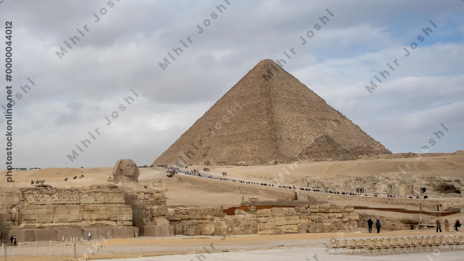 Giza, Egypt - Feb 6, 2024: Tourists walk toward the Great Pyramids of Giza with the iconic Sphinx in the foreground. Historic landmark near Cairo, Egypt.