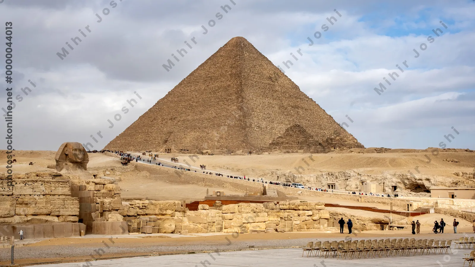 Giza, Egypt - Feb 6, 2024: Tourists walk toward the Great Pyramids of Giza with the iconic Sphinx in the foreground. Historic landmark near Cairo, Egypt.