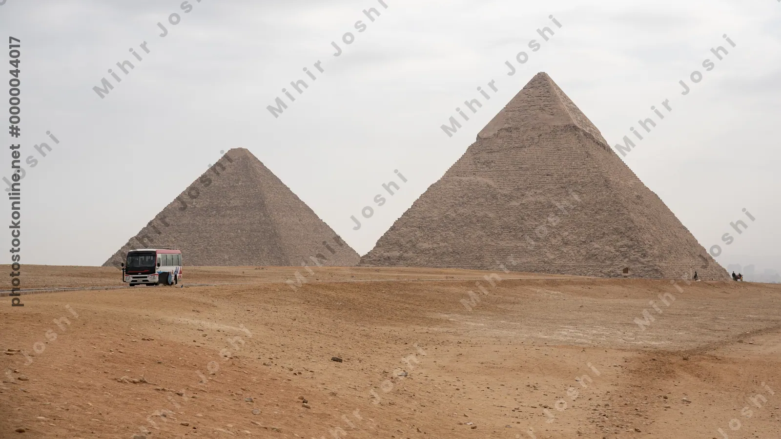 Giza, Egypt - Feb 6, 2024: A tourist bus passes near the Great Pyramids of Giza, viewed from the desert near Cairo, Egypt - an iconic archaeological destination.