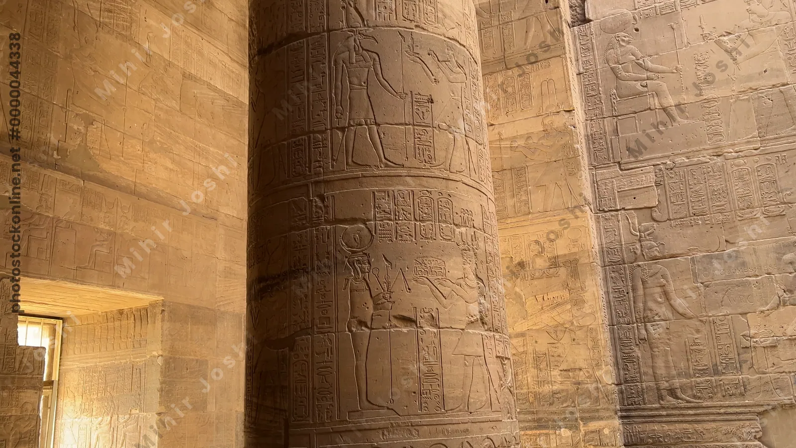 Agilkia, Egypt - Feb 7, 2024: Intricately carved pillar at the Temple of Philae in Aswan, Egypt, depicting ancient Egyptian gods and goddesses in detailed reliefs.