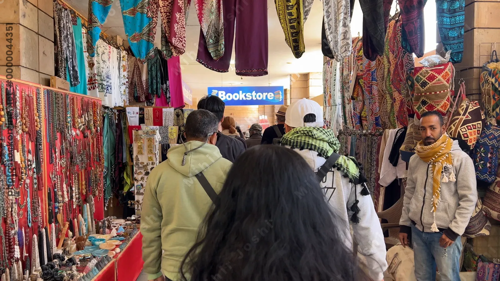 Aswan, Egypt - Feb 7, 2024: Visitors walking through colorful souvenir shops at a popular tourist destination in Egypt.