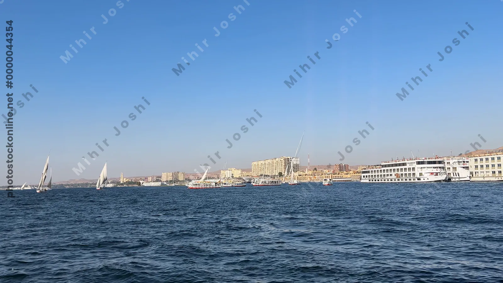 Aswan, Egypt - Feb 7, 2024: Scenic boat ride on the blue waters of the Nile River with traditional Egyptian feluccas in view.