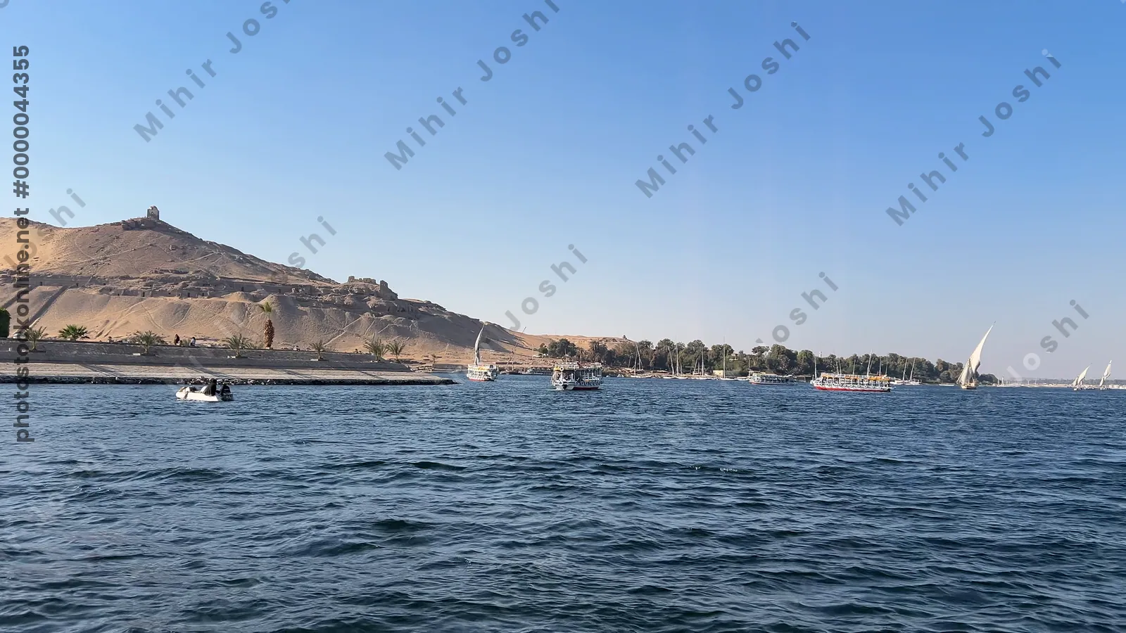 Aswan, Egypt - Feb 7, 2024: Ancient rock-cut Tombs of the Nobles on the hillside across the Nile River from Aswan, Egypt, seen from a boat ride.