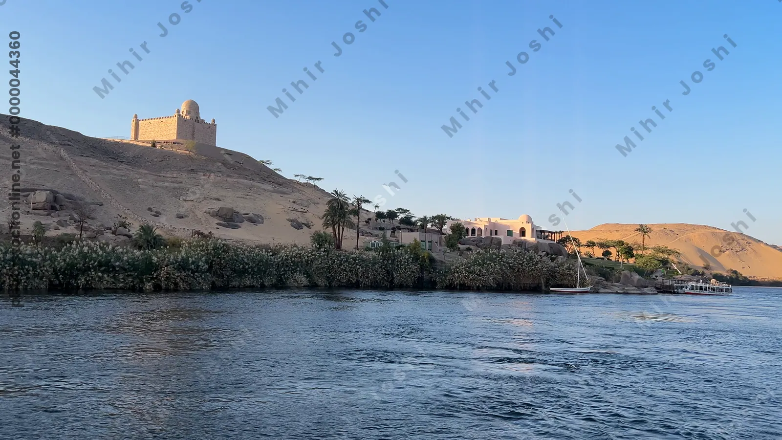 Aswan, Egypt - Feb 7, 2024: Scenic boat ride on the Nile River with the Mausoleum of Aga Khan visible on the desert hillside in Aswan, Egypt.
