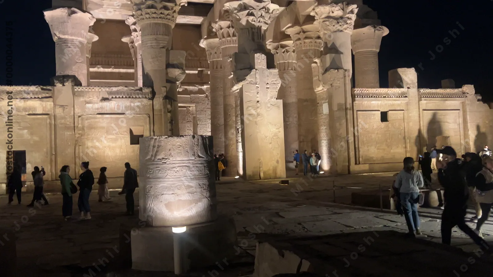 Kom Ombo, Egypt - Feb 8, 2025: Visitors at the Temple of Kom Ombo, illuminated at night with glowing sandstone columns and reliefs.
