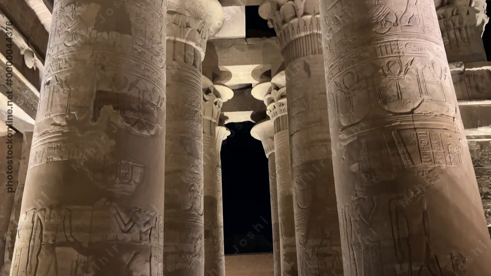 Kom Ombo, Egypt - Feb 8, 2025: Footage panning up massive carved pillars of the Temple of Kom Ombo, illuminated at night.