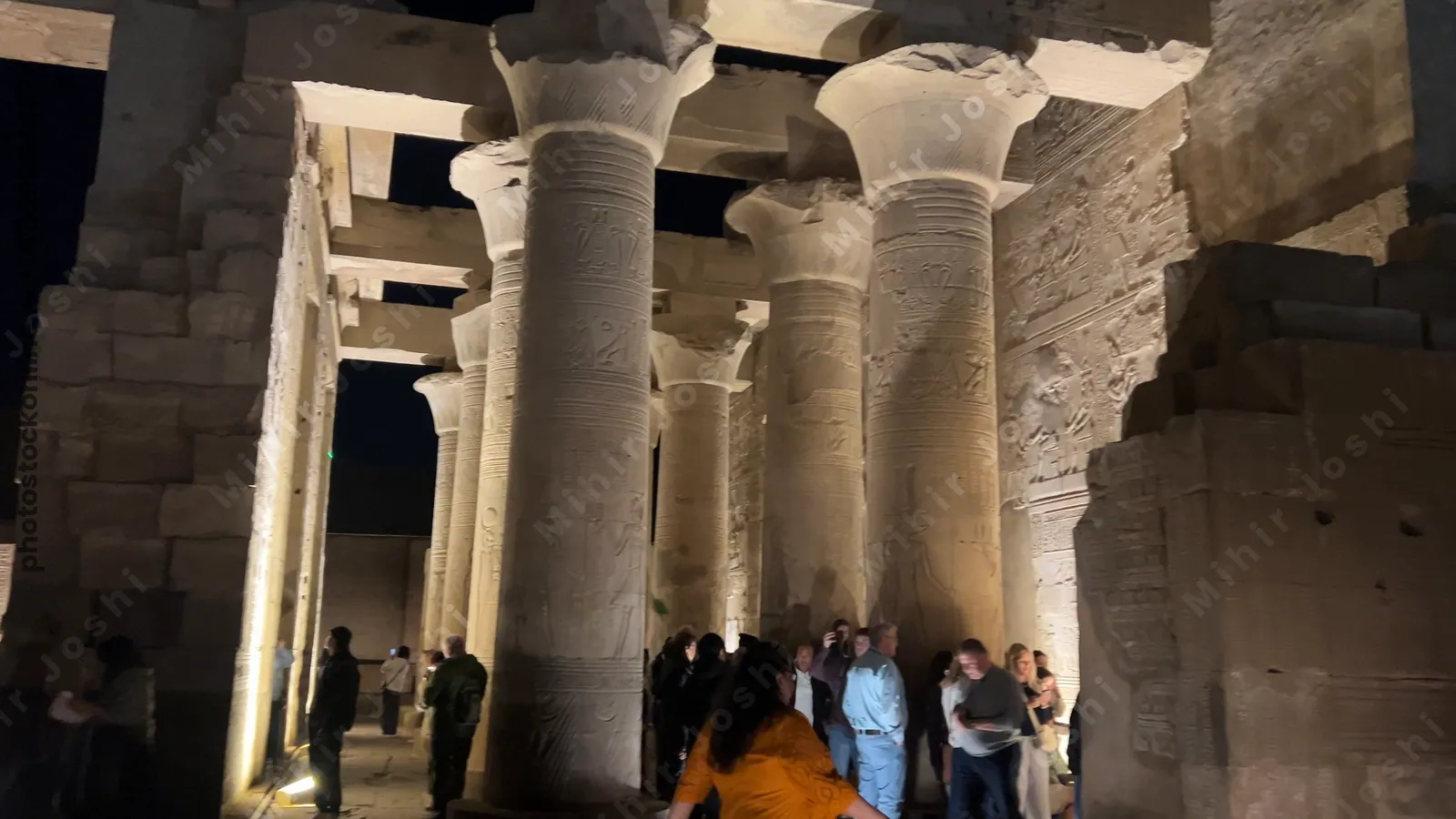 Kom Ombo, Egypt - Feb 8, 2025: Visitors at the Temple of Kom Ombo, illuminated at night with glowing sandstone columns and reliefs.