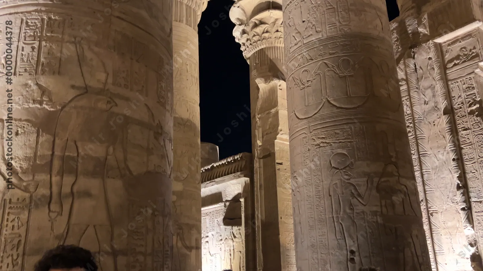 Kom Ombo, Egypt - Feb 8, 2025: Footage panning up massive carved pillars of the Temple of Kom Ombo, illuminated at night.