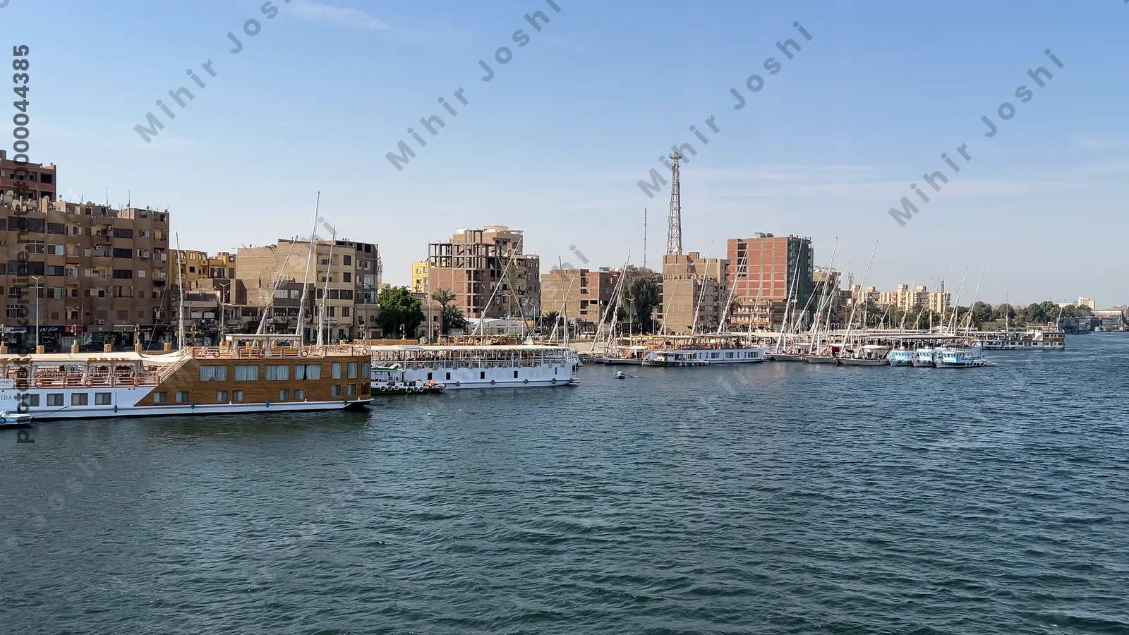 Nile River, Egypt - Feb 9, 2025: Footage from a cruise ship on the Nile showing the blue waters of the river, boats docked on its shores, and city buildings lining the riverbanks.