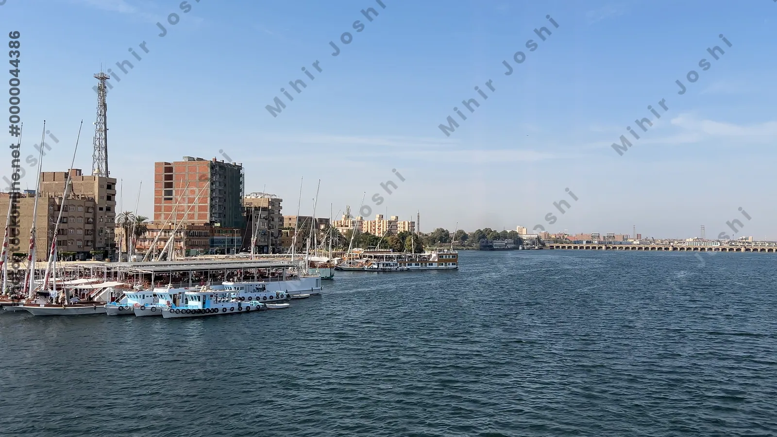 Nile River, Egypt - Feb 9, 2025: Footage from a cruise ship on the Nile showing the blue waters of the river, boats docked along the shore, and city buildings as the ship moves toward the Esna Lock in