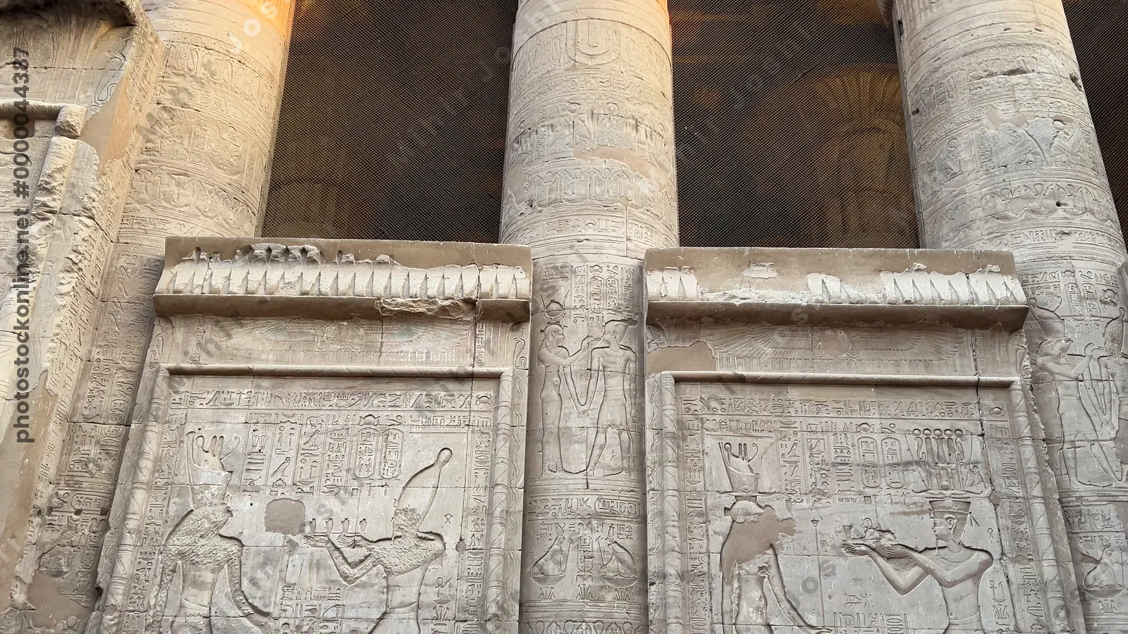Edfu, Egypt - Feb 9, 2025: Footage of carved reliefs showing a pharaoh making offerings to the gods with the tall stone pillars of the Temple of Edfu in Egypt.