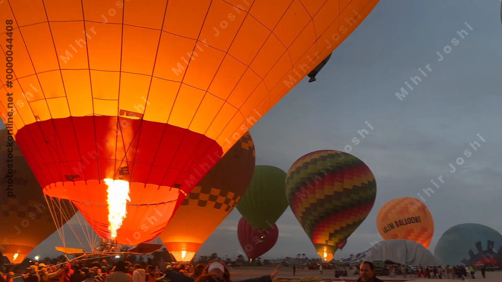 Luxor, Egypt - Feb 10, 2025: Colorful hot air balloons drifting above lush green fields at sunrise, offering a scenic aerial view of the landscape.