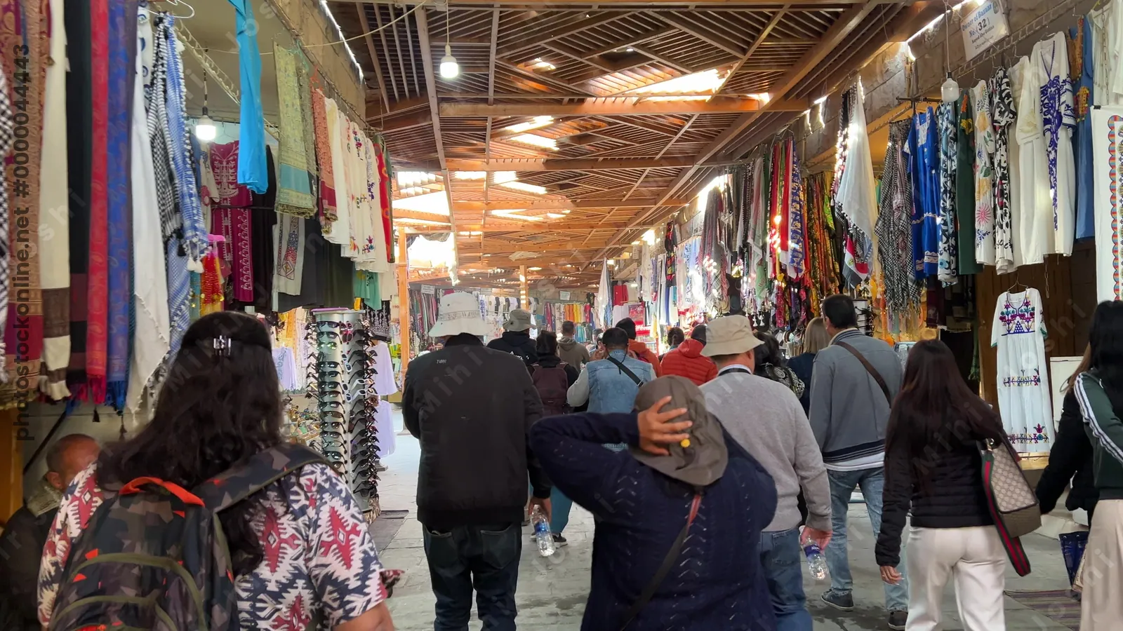 Luxor, Egypt - Feb 11, 2025: Tourists walking through souvenir shops at the Valley of the Kings, with traditional clothes and crafts for sale.
