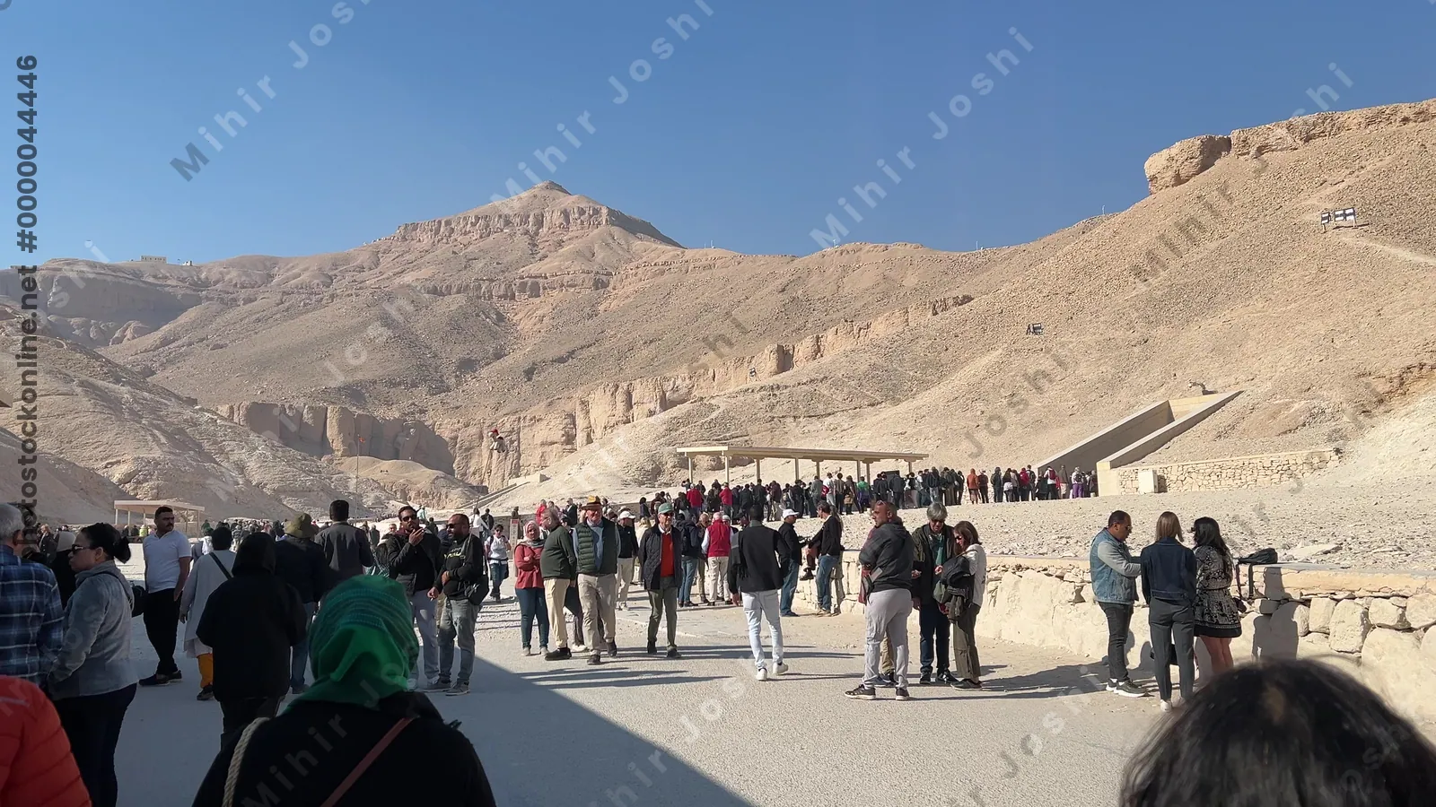 Luxor, Egypt - Feb 11, 2025: Visitors at the entrances of tombs in the Valley of the Kings, with desert mountains and heritage site surroundings.