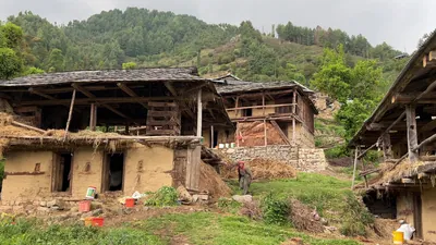 Janjehli, Himachal Pradesh, India - May 7, 2025:  Traditional rural houses and a local farmer in a Himalayan village in Janjehli, Mandi district, Himachal Pradesh, India.