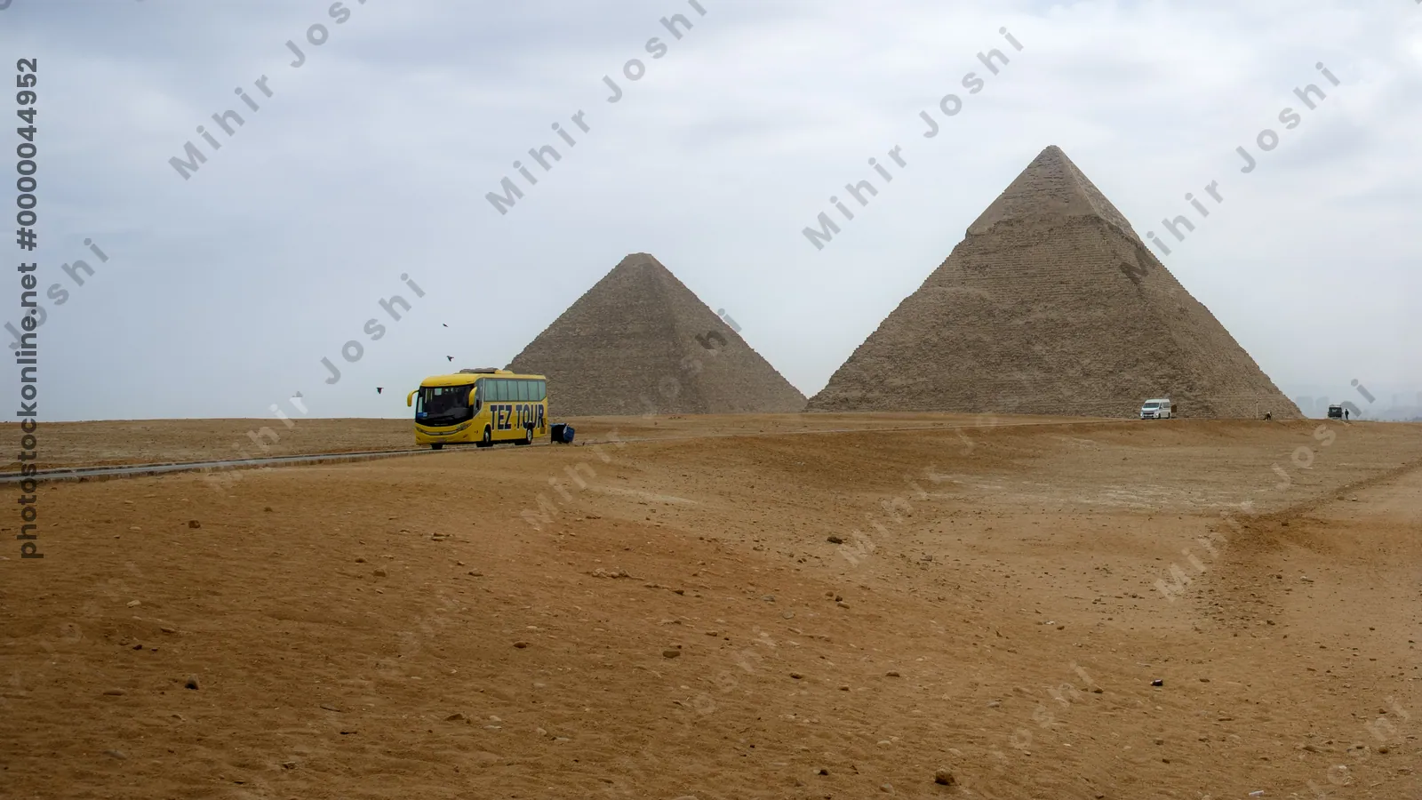 Giza, Egypt - Feb 6, 2024: A tourist bus passes near the Great Pyramids of Giza, viewed from the desert near Cairo, Egypt - an iconic archaeological destination.