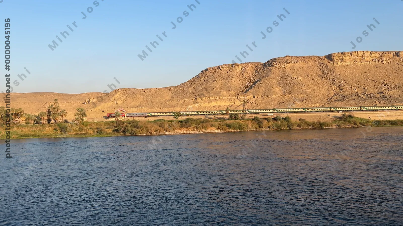 Aswan, Egypt - Feb 8, 2025: Footage from a Nile cruise ship capturing a train moving parallel to the river.