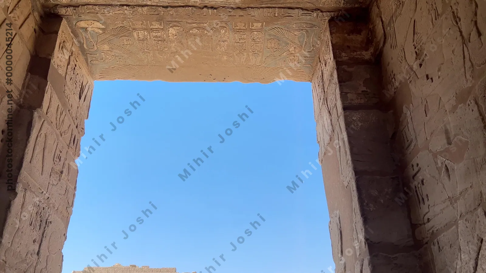Luxor, Egypt - Feb 11, 2025: Tourists walking through the Migdol Gate with the first pylon of the Mortuary Temple of Ramesses III visible at Medinet Habu.