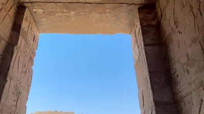 Luxor, Egypt - Feb 11, 2025: Tourists walking through the Migdol Gate with the first pylon of the Mortuary Temple of Ramesses III visible at Medinet Habu.