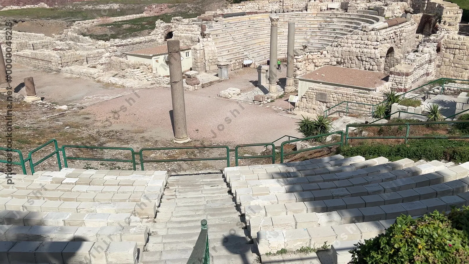 Alexandria, Egypt - Feb 13, 2025: Wide view of Roman theatre ruins at Kom El-Dikka archaeological site showing stone seating, columns, and city backdrop.