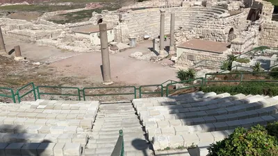 Alexandria, Egypt - Feb 13, 2025: Wide view of Roman theatre ruins at Kom El-Dikka archaeological site showing stone seating, columns, and city backdrop.